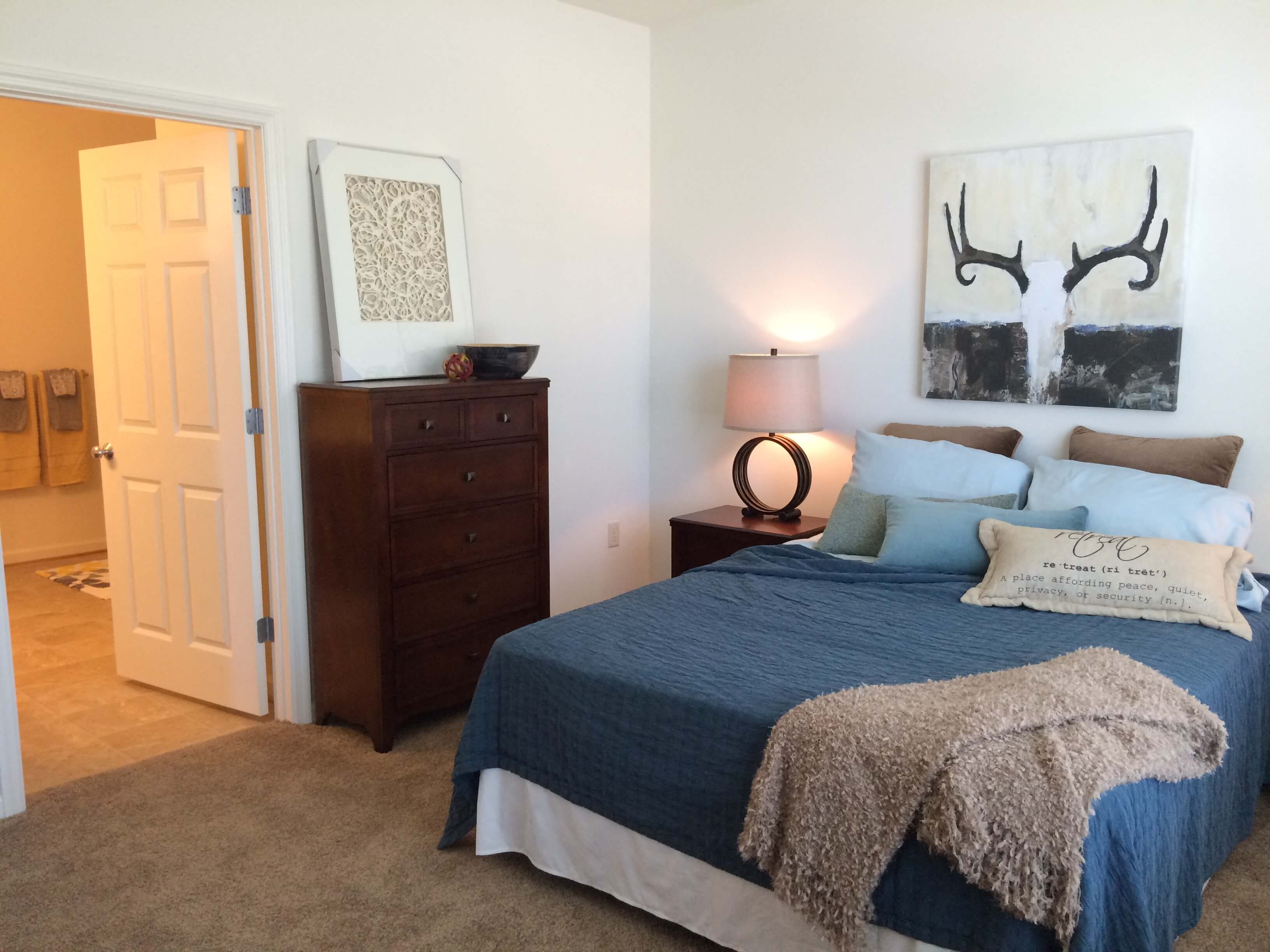 A bedroom with a bed, nightstand, and a painting on the wall.
