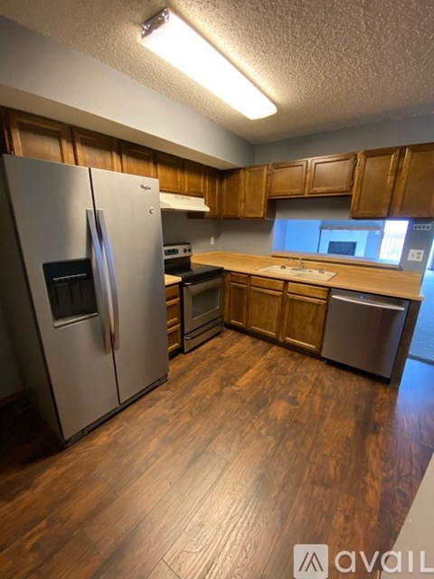 A kitchen with wooden cabinets and a stainless steel refrigerator.