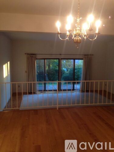 A room with a chandelier and a balcony with a white railing.
