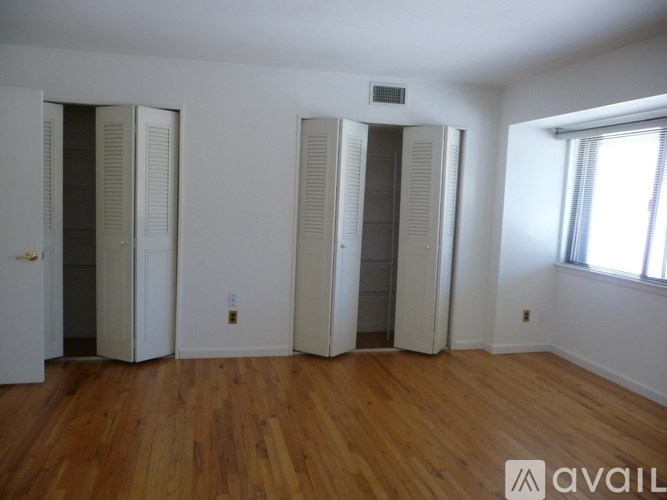 A room with wooden floors and three white closet doors.