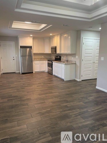 A kitchen with white cabinets and a wooden floor.