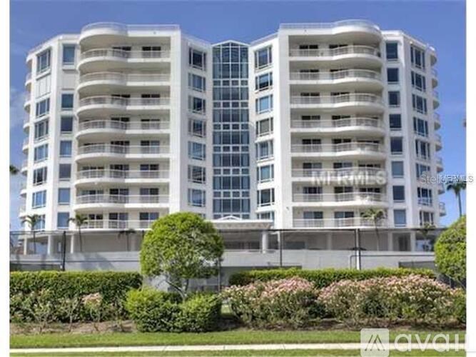 A white apartment building with balconies and a green lawn in front.