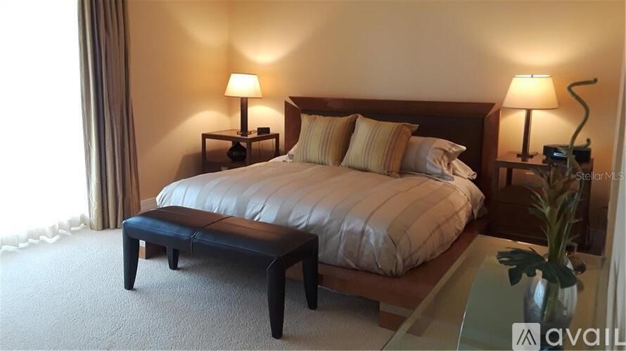 A well-lit bedroom with a large bed, a bench, and two lamps.