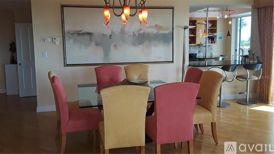 A dining room with a large painting on the wall and a chandelier hanging above the table.