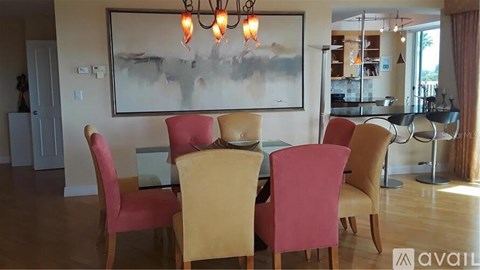 A dining room with a large painting on the wall and a chandelier hanging above the table.