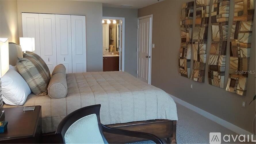 A bedroom with a bed, chair, and pictures on the wall.