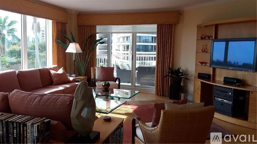 A living room with a red couch, a glass table, and a television.