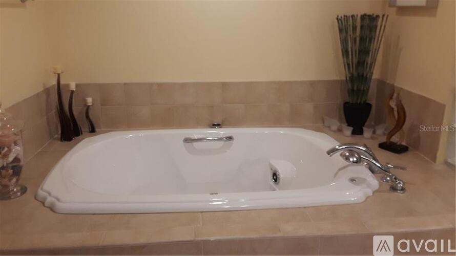 A white bathtub with a silver faucet and handle is in the bathroom.