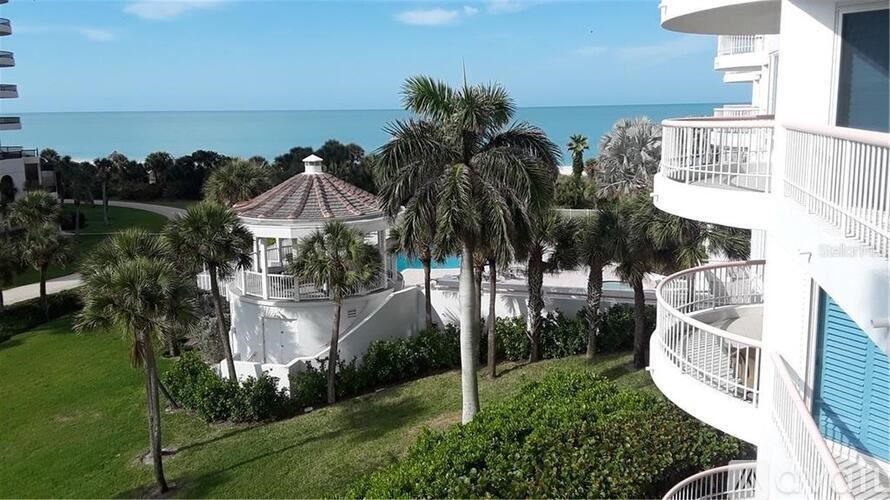 A white building with a gazebo in the middle of a grassy area.