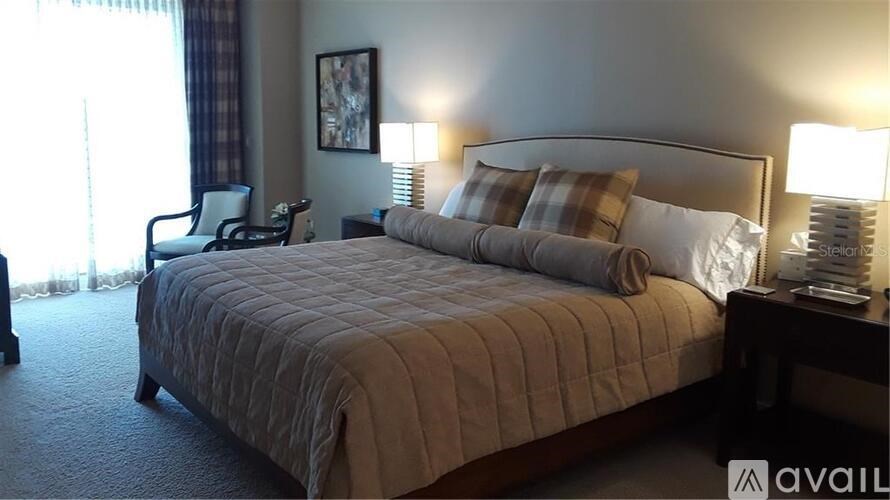 A bedroom with a large bed and a chair.