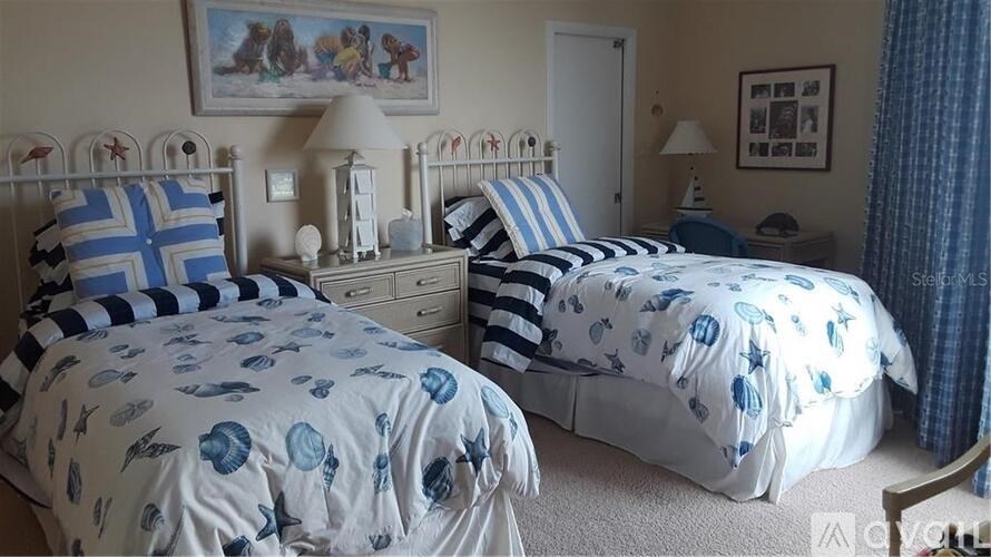 A bedroom with two beds, both covered in blue and white bedding.