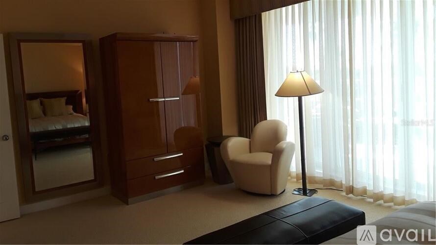 A bedroom with a bed, a chair, a cabinet, and a lamp.