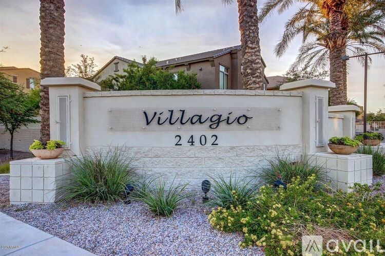 A sign that says "Villagio" and "2402" in front of some plants and trees.