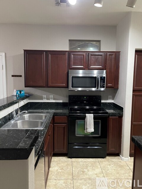 A kitchen with brown cabinets and black countertops.