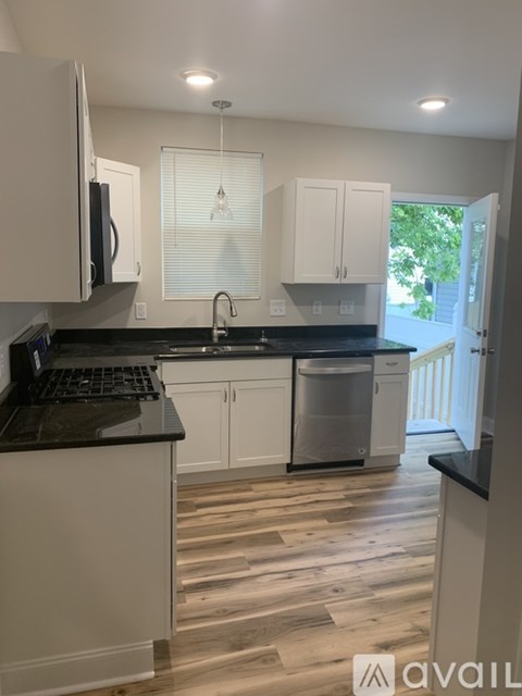 A kitchen with white cabinets and black countertops.