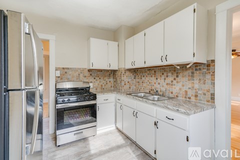 A kitchen with white cabinets and a tiled backsplash.