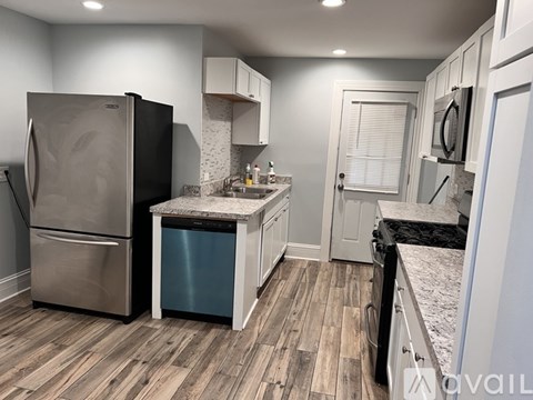 A kitchen with a stainless steel refrigerator and a blue trash can.