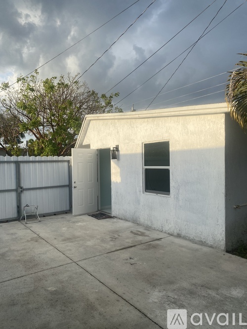 A small white building with a door and a window is surrounded by a fence.