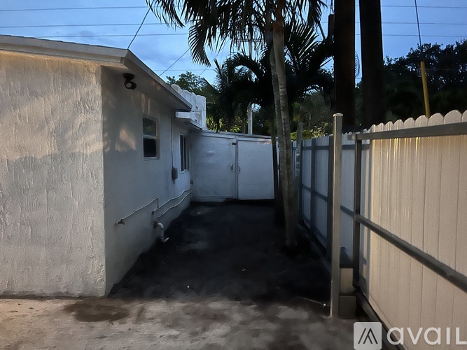 A backyard with a white fence and a small building.