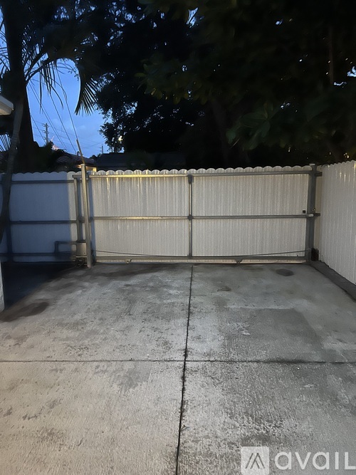 A concrete driveway leads to a white fence.