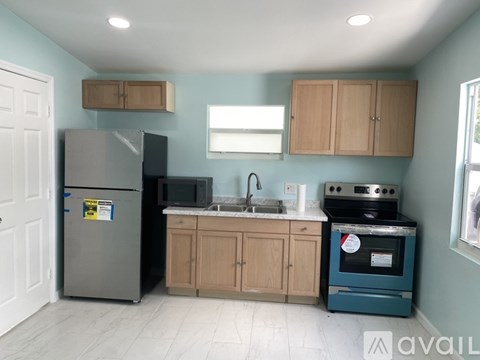 A kitchen with a blue wall and a black fridge.