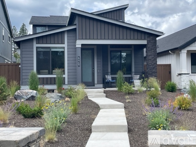A modern house with a grey exterior and a stone pathway leading to the entrance.