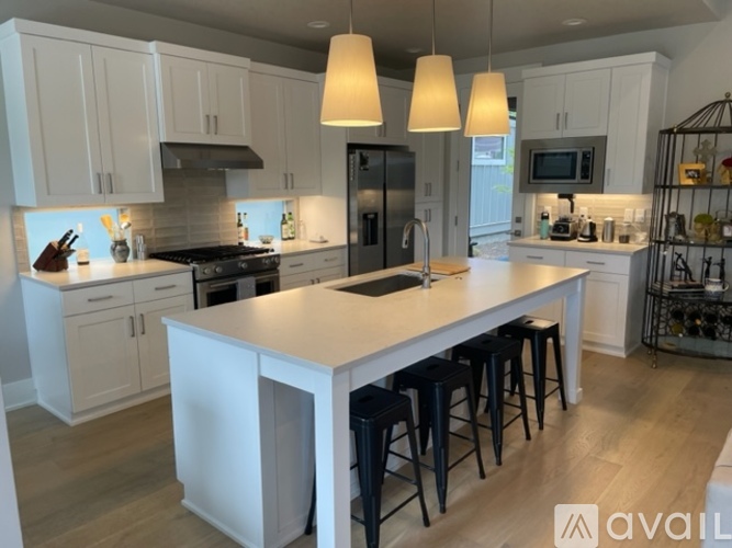 A kitchen with white cabinets and a large island with black stools.