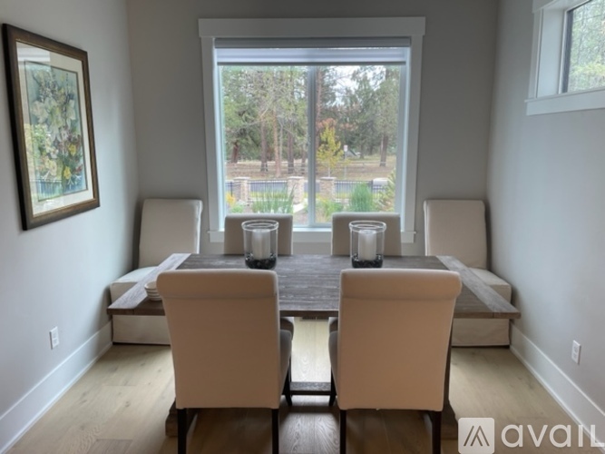 A dining room with a table and chairs and a window overlooking a yard.