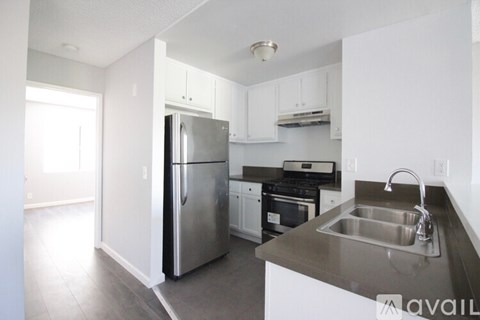A kitchen with a stainless steel refrigerator and a stainless steel sink.