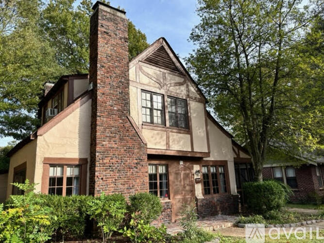 A house with a red brick chimney and a large tree in front.