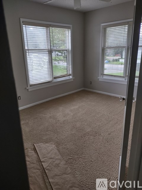 A room with two windows and carpeted floor.