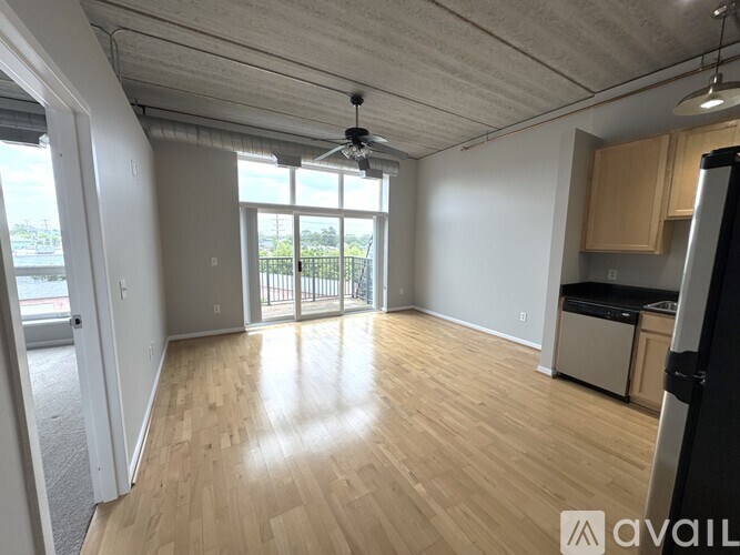 A spacious room with wooden flooring and a ceiling fan.
