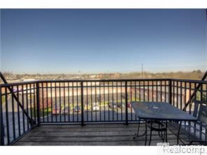 A balcony with a table and chairs overlooking a parking lot.