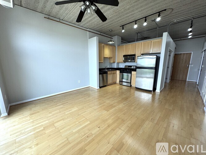 A spacious kitchen with wooden flooring and a ceiling fan.