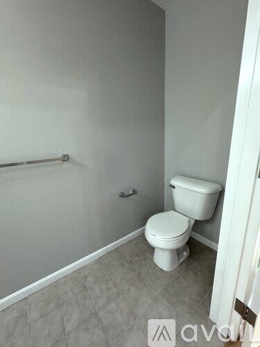A white toilet sits in a bathroom with a white shower curtain.