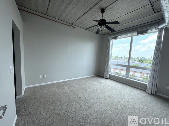 A room with a ceiling fan and a large window overlooking a cityscape.