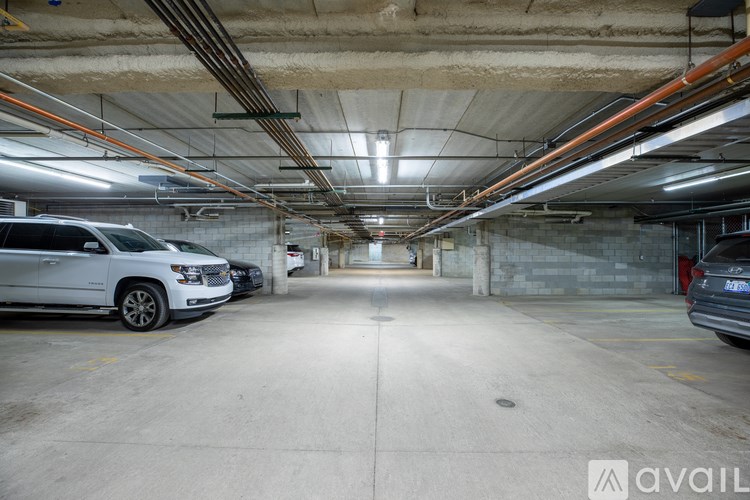 A long, narrow parking garage with two cars parked on the left side.