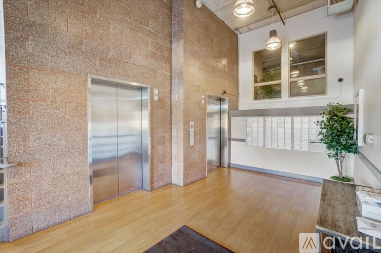 A hallway with a wooden floor, stone walls, and two elevators.