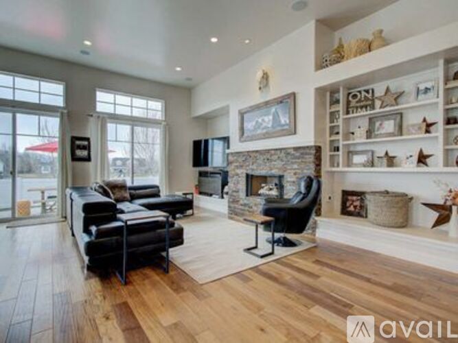 A living room with a black leather sofa and a stone fireplace.