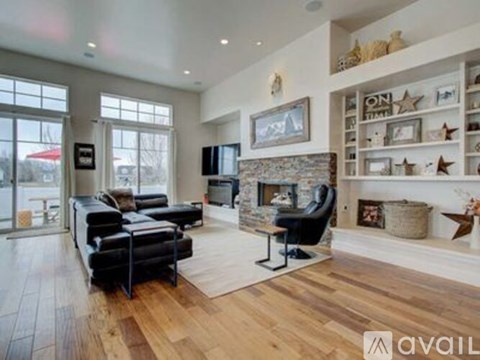 A living room with a black leather sofa and a stone fireplace.