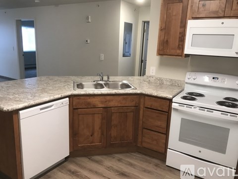 A kitchen with a white dishwasher and white oven with wooden cabinets.
