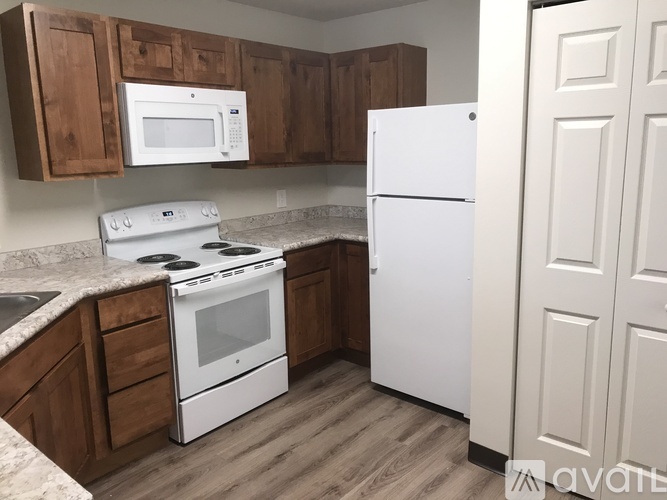 A kitchen with white appliances and wooden cabinets.
