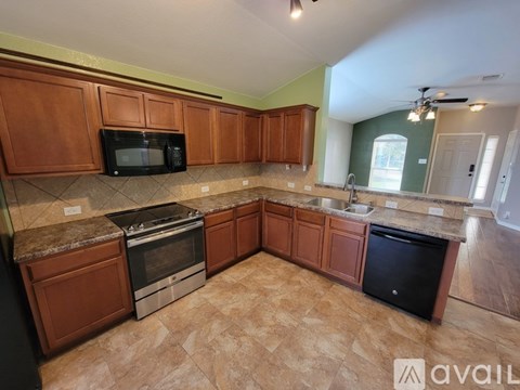 A kitchen with brown cabinets and a black fridge.