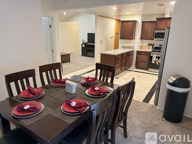 A dining room with a table set for six with red napkins.