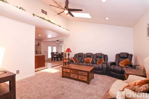 A living room with a grey carpet and a black leather sofa.