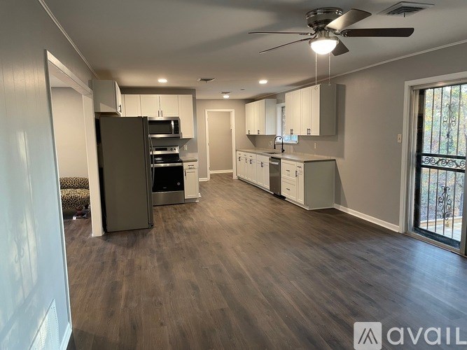 A spacious kitchen and living room with a ceiling fan and hardwood floors.