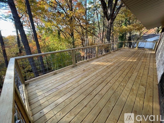 A wooden deck with a metal railing overlooks a forest.
