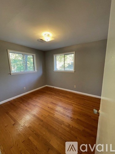 A room with wooden floors and two windows.