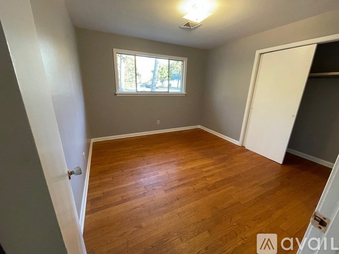 A room with wooden flooring and a window.
