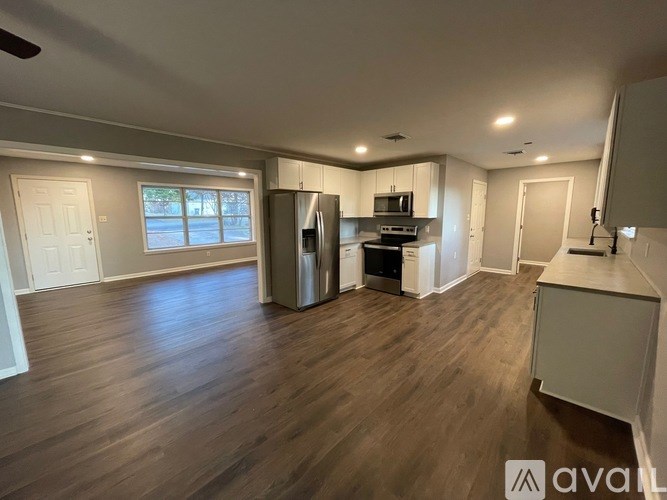 A spacious kitchen and living room with wood flooring and modern appliances.